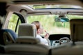 Concept of danger driving. Young woman driver red haired teenage girl painting her lips doing applying make up while driving the