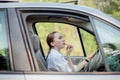 Concept of danger driving. Young woman driver red haired teenage girl painting her lips doing applying make up while driving the