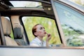 Concept of danger driving. Young woman driver red haired teenage girl painting her lips doing applying make up while driving the Royalty Free Stock Photo