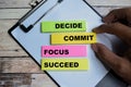 Concept of Decide Commit Focus Succeed write on sticky notes on Wooden Table