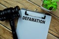 Concept of Defamation write on paperwork with gavel isolated on Wooden Table