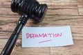 Concept of Defamation write on sticky notes isolated on Wooden Table Royalty Free Stock Photo