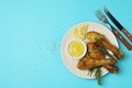 Concept of delicious eating with plate of roast chicken drumsticks on blue background