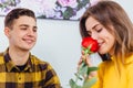 Sensual girl smells a rose her boyfriend gave her. He looks at her with love, pleased that she likes his present.