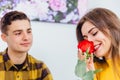 Sensual girl smells a rose her boyfriend gave her. He looks at her with love, pleased that she likes his present.