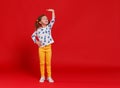 Concept of development and growth, kid girl measuring height on red colored background