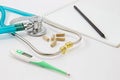 Thermometer and stethoscope, pills, pen, notebook on the doctor desk Royalty Free Stock Photo