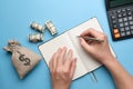 The concept of a diary with debtors. Hands with a pen on the diary next to a bag of money and a calculator Royalty Free Stock Photo