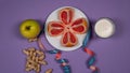 Concept diet - healthy food with apple, grapefruit, peanut, yogurt and measuring tape on purple background