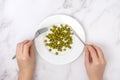 The concept of diet and weight loss. Women`s hands with a fork and a table knife over a plate of green peas Royalty Free Stock Photo