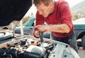 The concept of disability of people and their adaptation to life. A blond disabled man repairs a car, works with a screwdriver.
