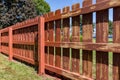 Wood privacy fence in yard half with new, fresh painted and half with peeling paint on boards