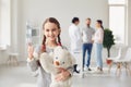 Girl with a toy stands against the background of the doctor and parents standing in the clinic office.