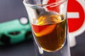 Concept of driving while intoxicated. A glass of whiskey with an inverted machine and a road sign is prohibited from entering