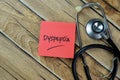 Concept of Dyspepsia write on sticky notes with stethoscope isolated on Wooden Table