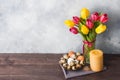 Concept Easter, tulips in a vase and a basket of eggs, a candle on a gray background. Copy space for product or text Royalty Free Stock Photo