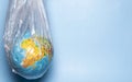 The concept of ecology. Globe in plastic wrap on a blue background. plastic waste environmental pollution concept.