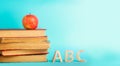 The concept of education. apple, books and alphabe, blue background, place for text, back to school, copy space