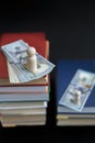 Concept of education and income. Wooden figures dollars and books on a black background. vertical photo.