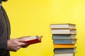 Concept of education. A man holds a book in his hands and reads it. Nearby is a stack of books. Yellow background Royalty Free Stock Photo