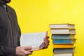 Concept of education. A man holds a book in his hands and reads it. Nearby is a stack of books. Yellow background. Copy space Royalty Free Stock Photo