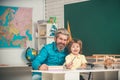 Concept of education and reading. Kid and teacher is learning in class on background of blackboard. School kids. Cute Royalty Free Stock Photo