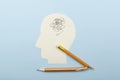 Concept of emotional catatonia and mental block.Top view of paper head as a symbol of mess with head and broken pencil on the blue Royalty Free Stock Photo