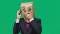 Concept of emotions, gestures. a man with paper bags on his head, with a painted emoticon, fear. talking on a cell phone Royalty Free Stock Photo