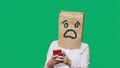 Concept of emotions, gestures. a man with paper bags on his head, with a painted emoticon, fear. talking on a cell phone Royalty Free Stock Photo