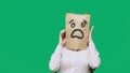 Concept of emotions, gestures. a man with paper bags on his head, with a painted emoticon, fear. talking on a cell phone Royalty Free Stock Photo