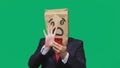 Concept of emotions, gestures. a man with paper bags on his head, with a painted emoticon, fear. talking on a cell phone Royalty Free Stock Photo
