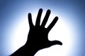 Silhouette of five fingers on a man`s hand with a bright light spot. The concept of entreaty for help or greetings. Blue Royalty Free Stock Photo