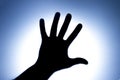 Silhouette of five fingers on a man`s hand with a bright light spot. The concept of entreaty for help or greetings. Blue