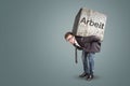 Businessman bending under a heavy stone with the German word `Arbeit` written on it Royalty Free Stock Photo