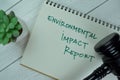 Concept of Environmental Impact Report write on a book with gavel isolated on Wooden Table