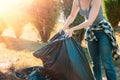 The concept of environmental pollution and Earth Day. A female volunteer does cleaning in the Park in front of the house, stacking