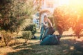 The concept of environmental pollution and Earth Day. A female volunteer does cleaning in the Park in front of the house, tying