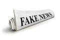 Concept of false news. Rolled Up Newspaper with Headline of Fake News Isolated on White Background. Royalty Free Stock Photo