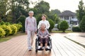 senior grandma sitting on wheelchair,smiling,daughter and son in law walking with her in the city park Royalty Free Stock Photo