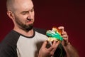 The concept of fast food and ecology. A bald man with a beard looks disgustedly into the plastic filling of a hamburger. Burgundy