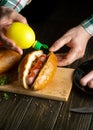 The concept of fast or street cooking in the kitchen. Cooking a hot dog with the hands of a street chef. Adding mustard to a hot Royalty Free Stock Photo