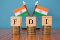 Concept of FDI or foreign Direct Investment on India in wooden block letters on stack of coins with Indian Flag as a background Royalty Free Stock Photo