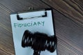 Concept of Fiduciary write on a paperwork with gavel isolated on Wooden Table