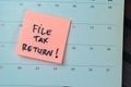 Concept of File Tax Return! write on sticky notes with Calendar isolated on Wooden Table Royalty Free Stock Photo