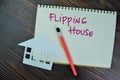 Concept of Flipping House write on a book isolated on Wooden Table