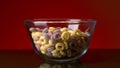Concept of food and breakfast. Stock footage. Close up of colorful ring corn flakes in a transparent glass bowl on dark Royalty Free Stock Photo