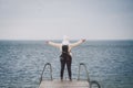 Concept of freedom relaxation. woman relaxing on pier. Backpacker hiker woman with backpack on sea wooden pier stands arms Royalty Free Stock Photo