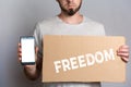 Concept of freedoms and human rights. A man with a cardboard and a phone in his hand. Text freedom and mock up