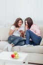 Two roommates using their smartphones at home sitting on a sofa in the living room.