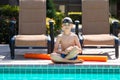 Oudoor summer activity. Concept of fun, health and vacation. Boy eight years old in swim glasses sits near a pool in hot